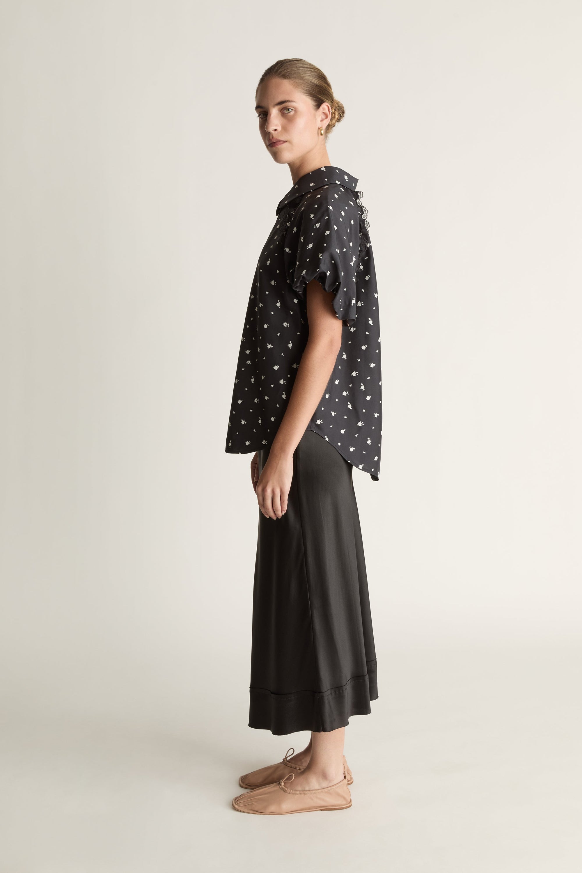 Woman wearing a black patterned blouse and black skirt on a white background