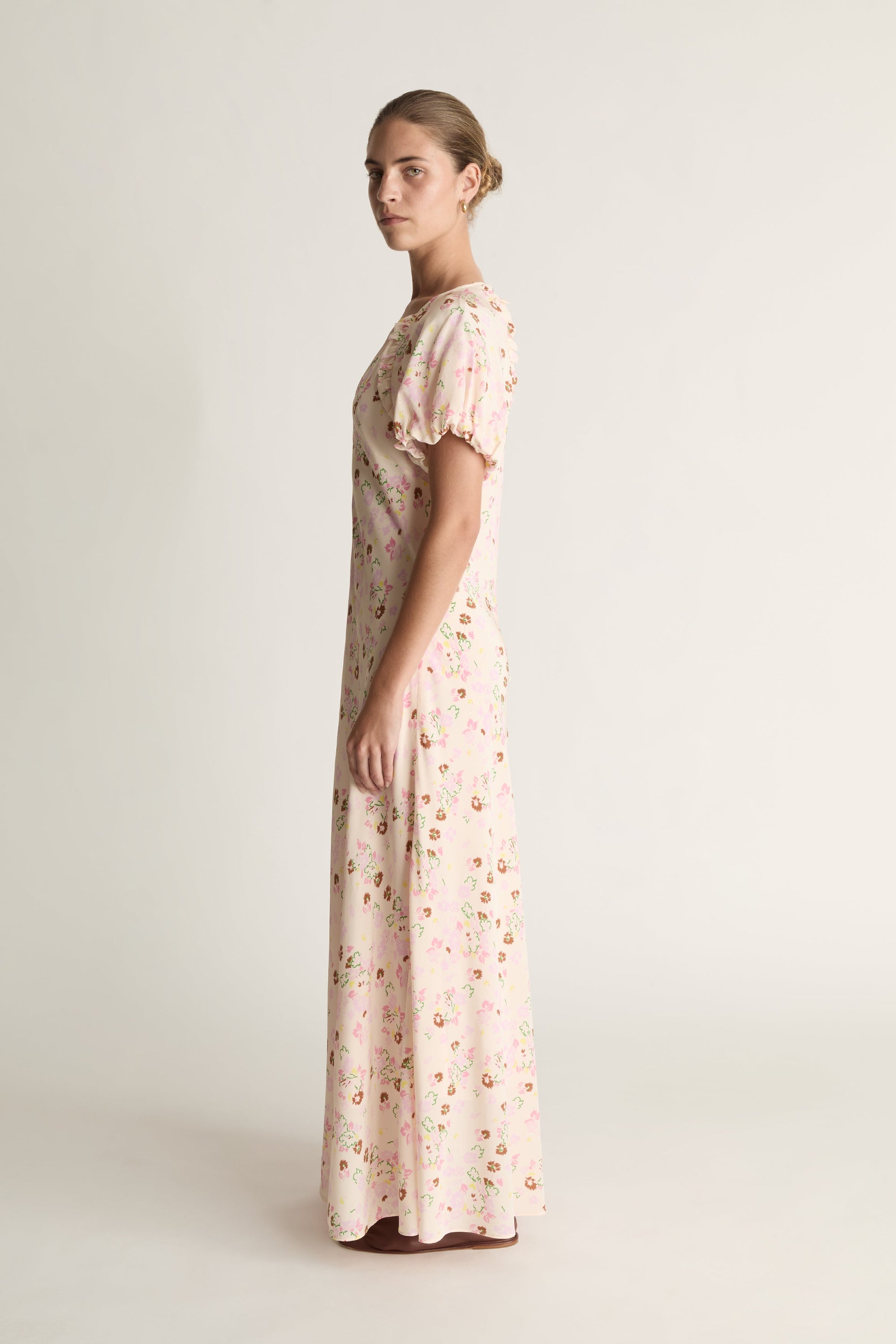 Woman wearing a long floral dress on a plain background