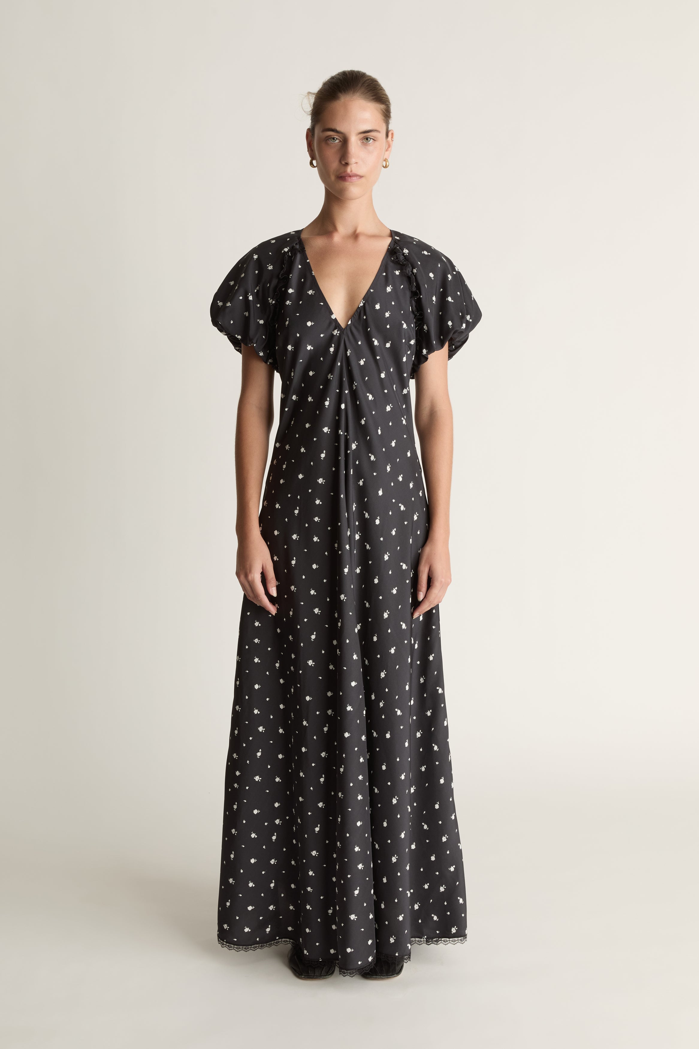 Woman wearing a black dress with white patterns on a plain background