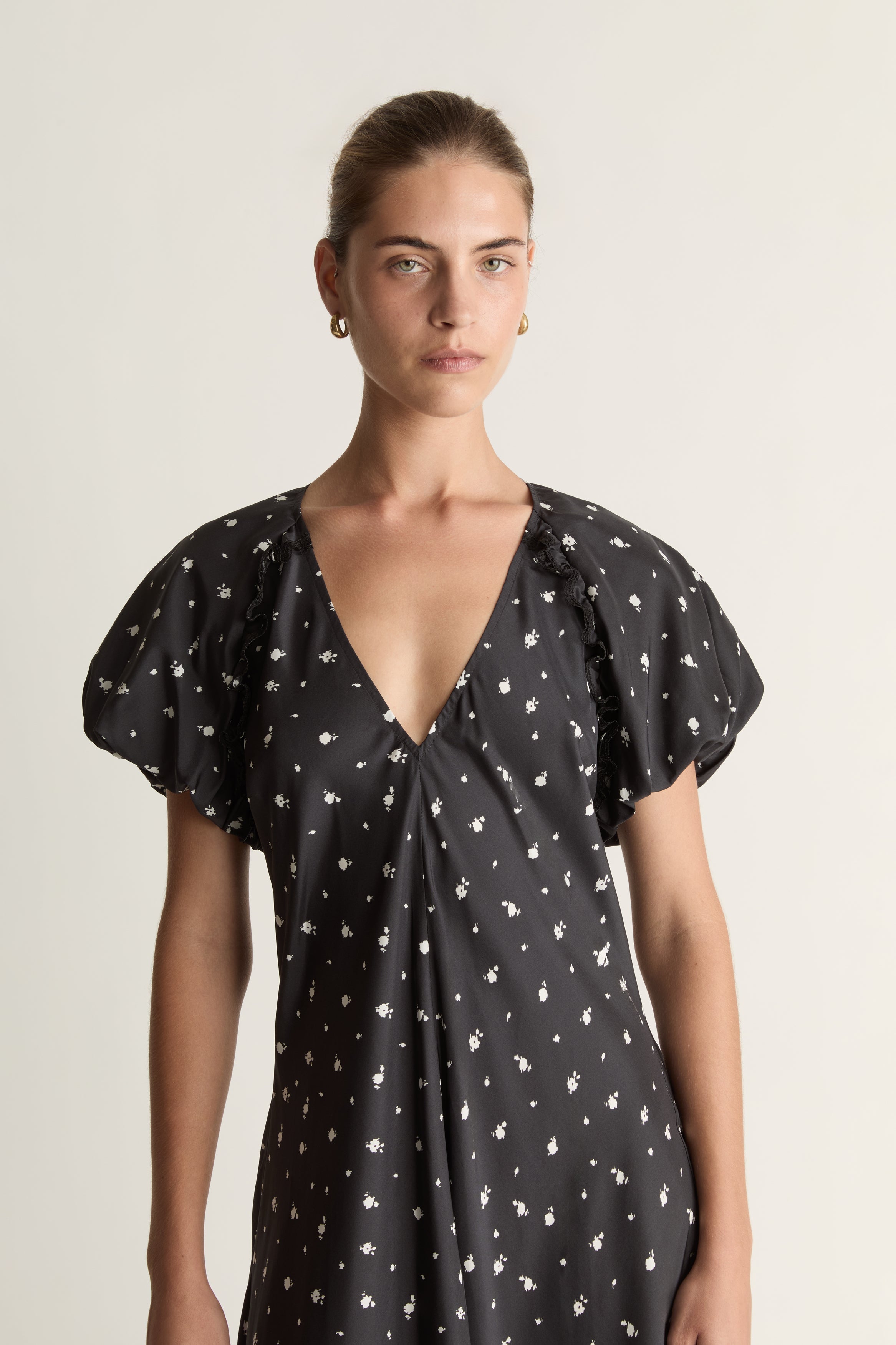 Woman wearing a black dress with white patterns on a plain background