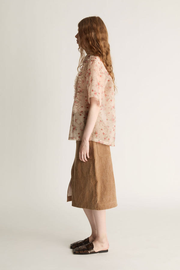 Person wearing a floral blouse and brown skirt on a white background