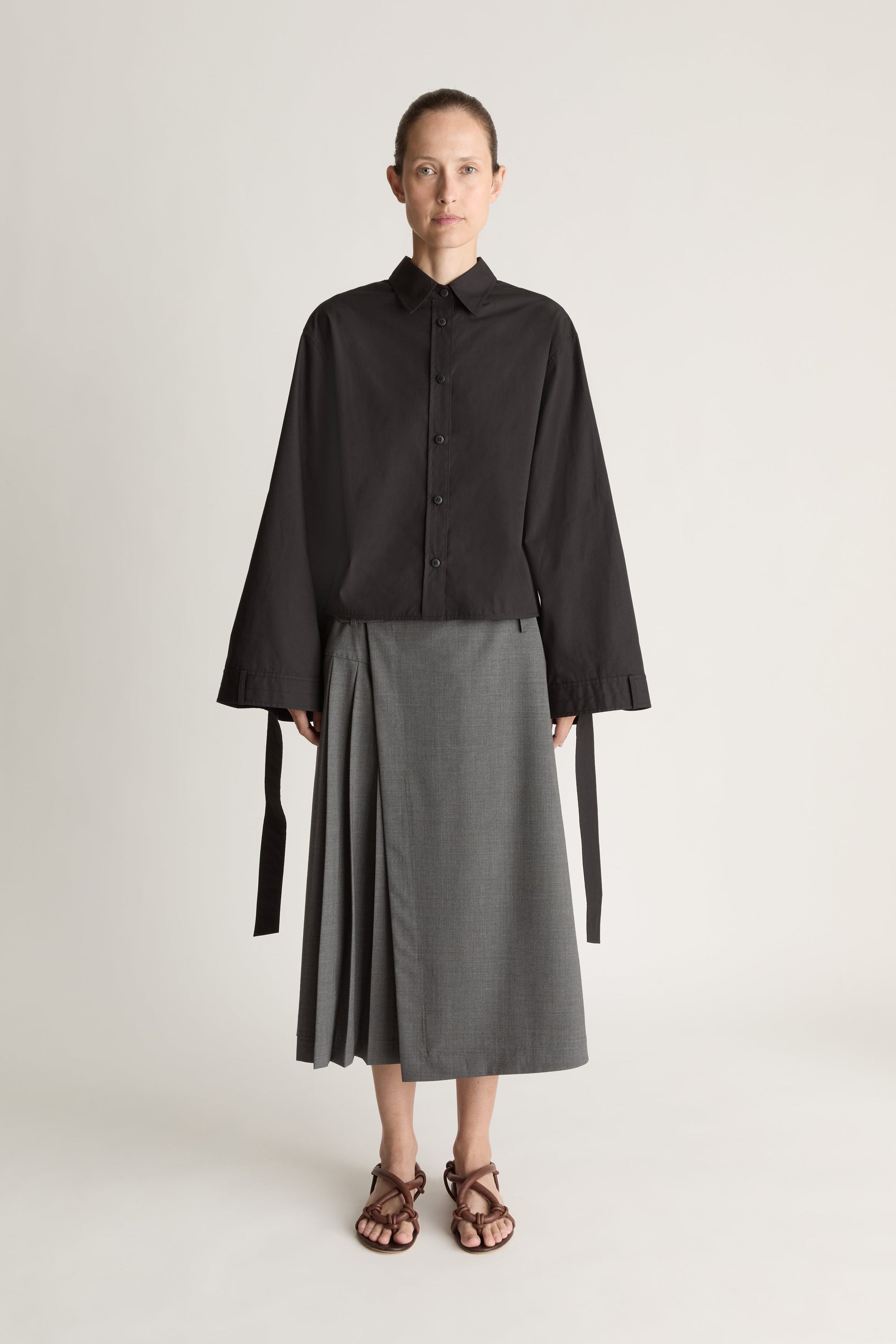 Person wearing a black shirt and gray skirt on a white background