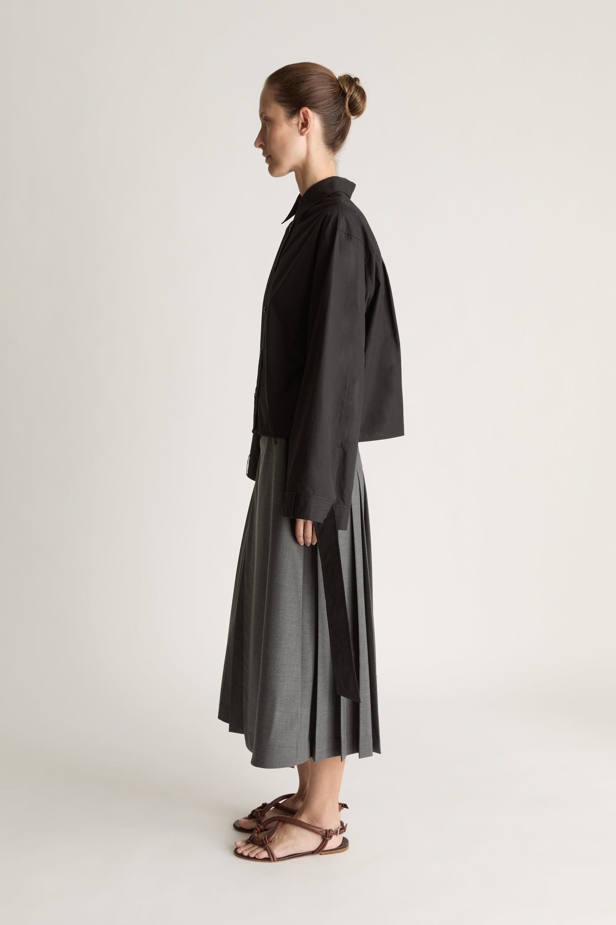 Person wearing a black shirt and gray skirt on a white background