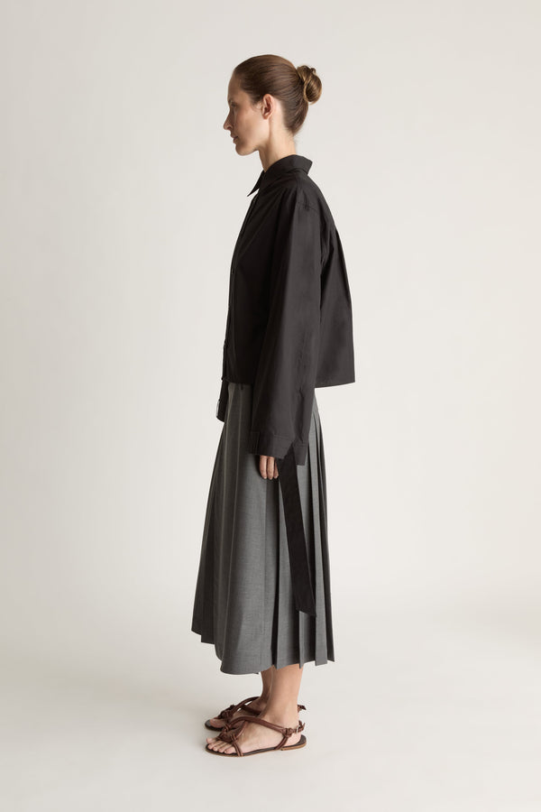 Person wearing a black shirt and gray skirt on a white background