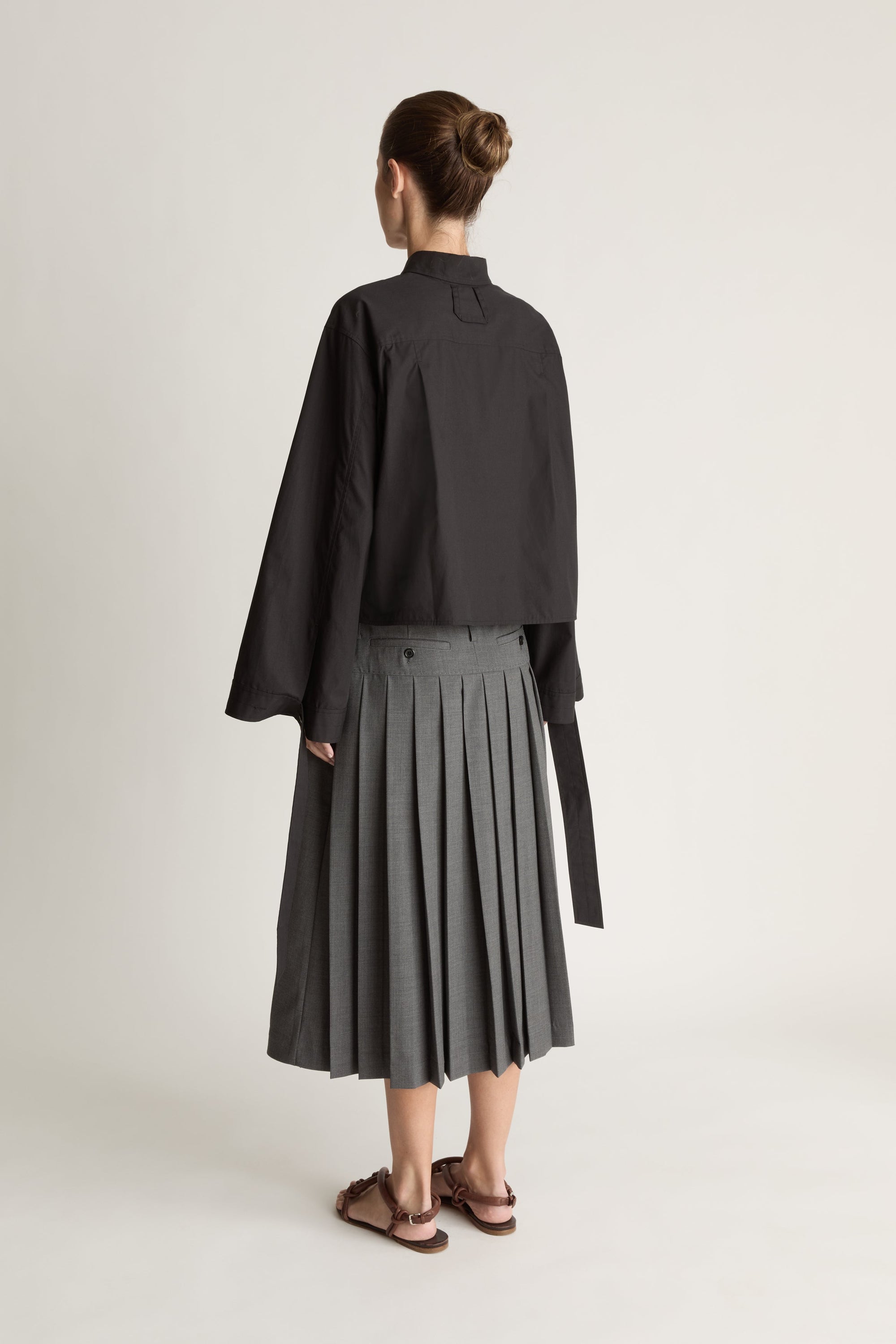 Person wearing a black shirt and gray skirt on a white background