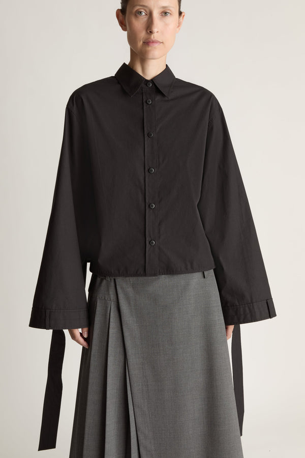 Person wearing a black shirt and gray skirt on a white background