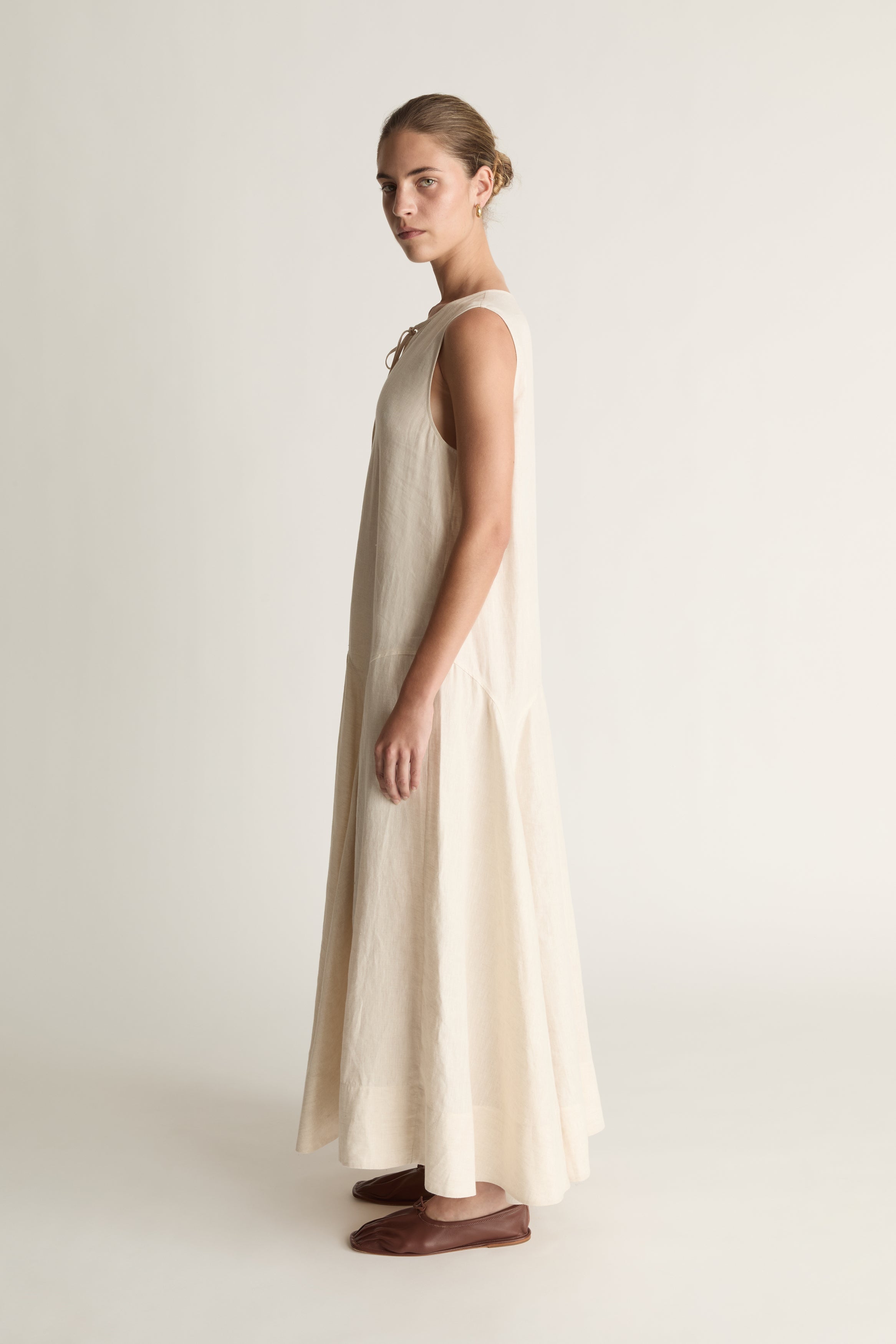 Woman wearing a long beige dress on a white background