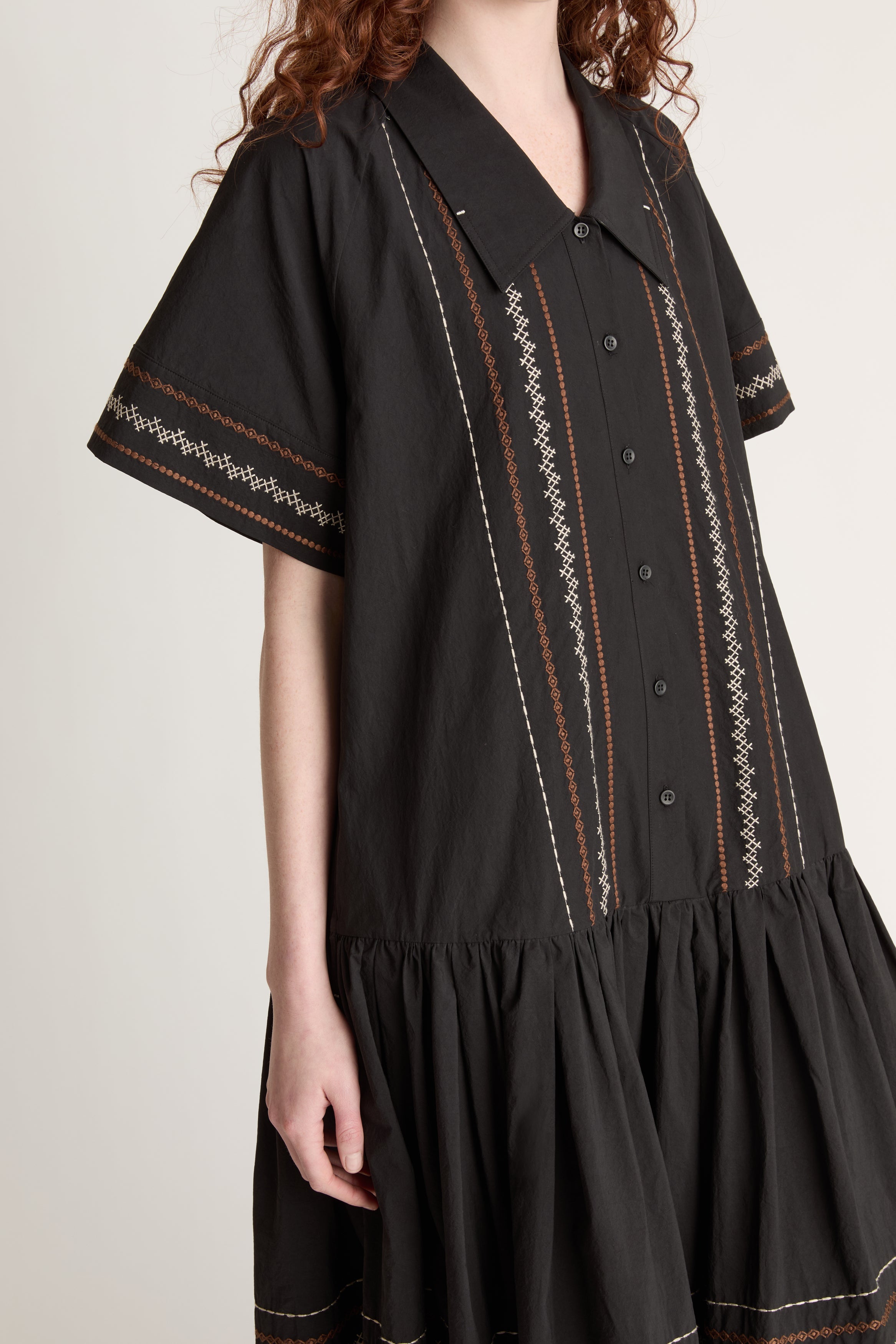 Woman wearing a black dress with patterned details on a white background