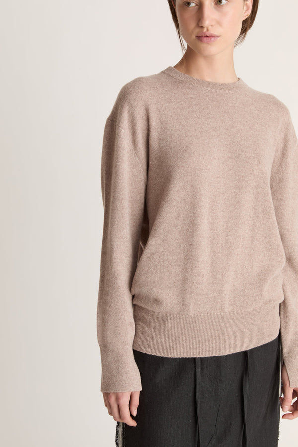 Person wearing a beige sweater and black skirt on a white background
