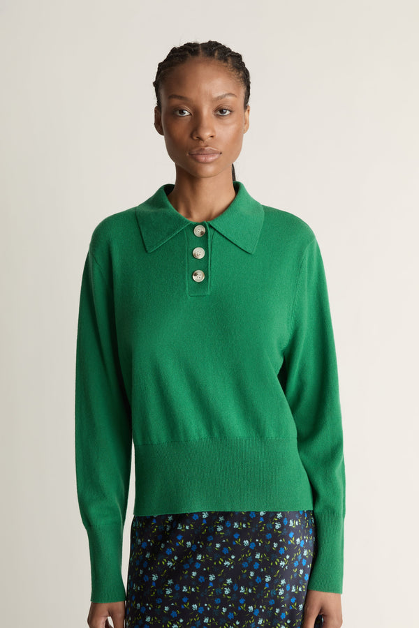 Woman wearing a green sweater and patterned skirt on a white background