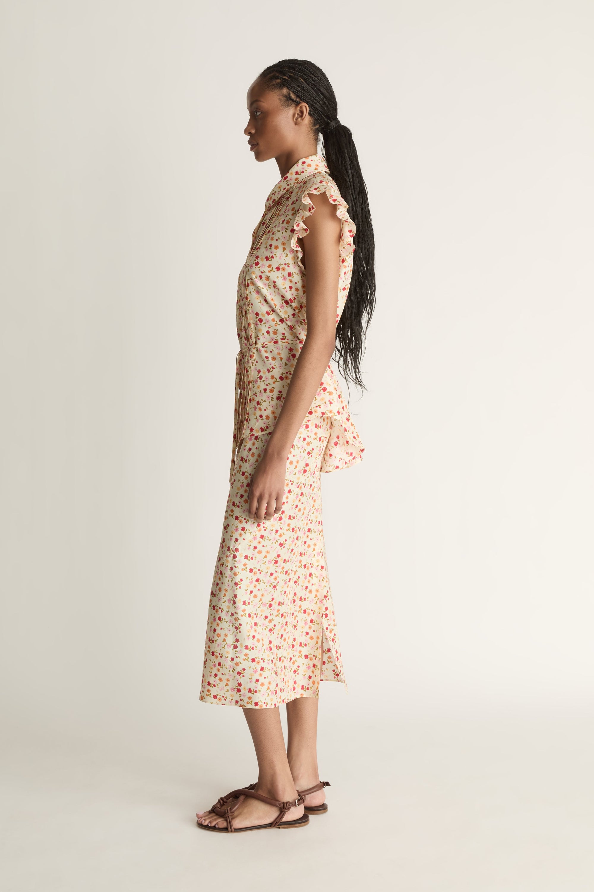 A woman wearing a floral shirt and skirt on a plain background