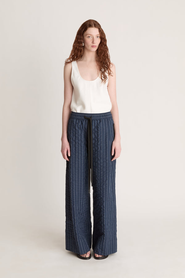 Woman wearing a white top and blue striped pants on a white background