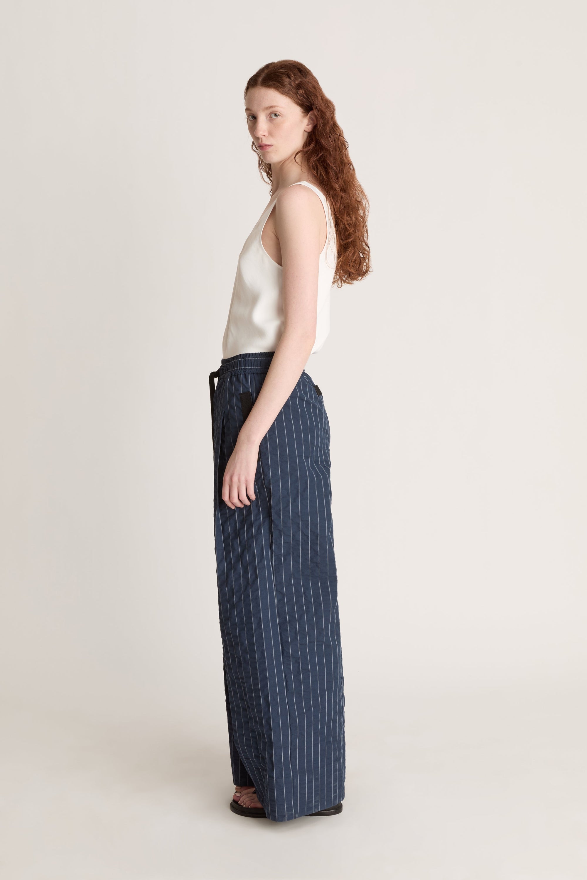 Woman wearing a white top and blue striped pants on a white background