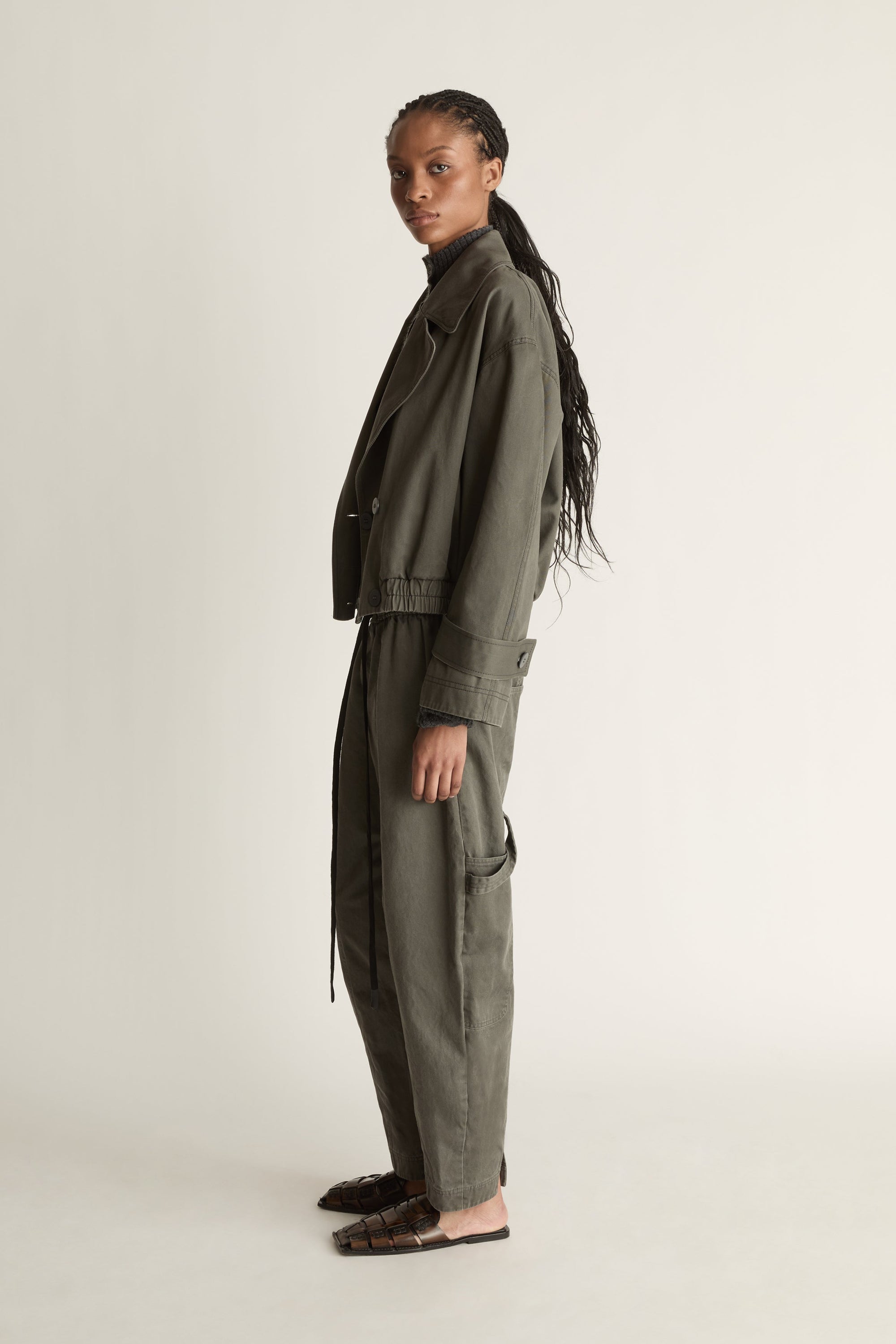 Person wearing a green coat and pants on a plain background