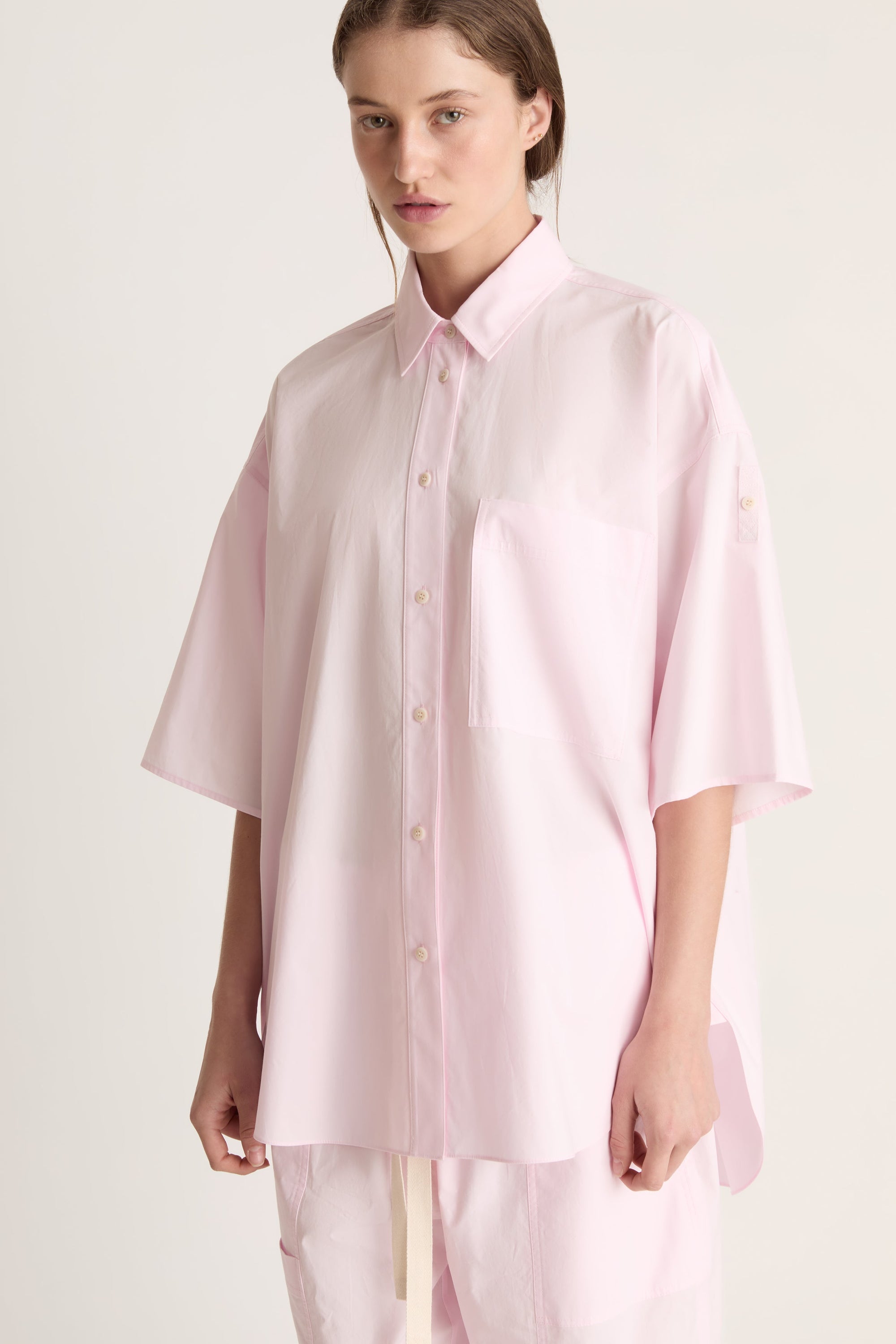 Person wearing a light pink shirt and pants on a white background