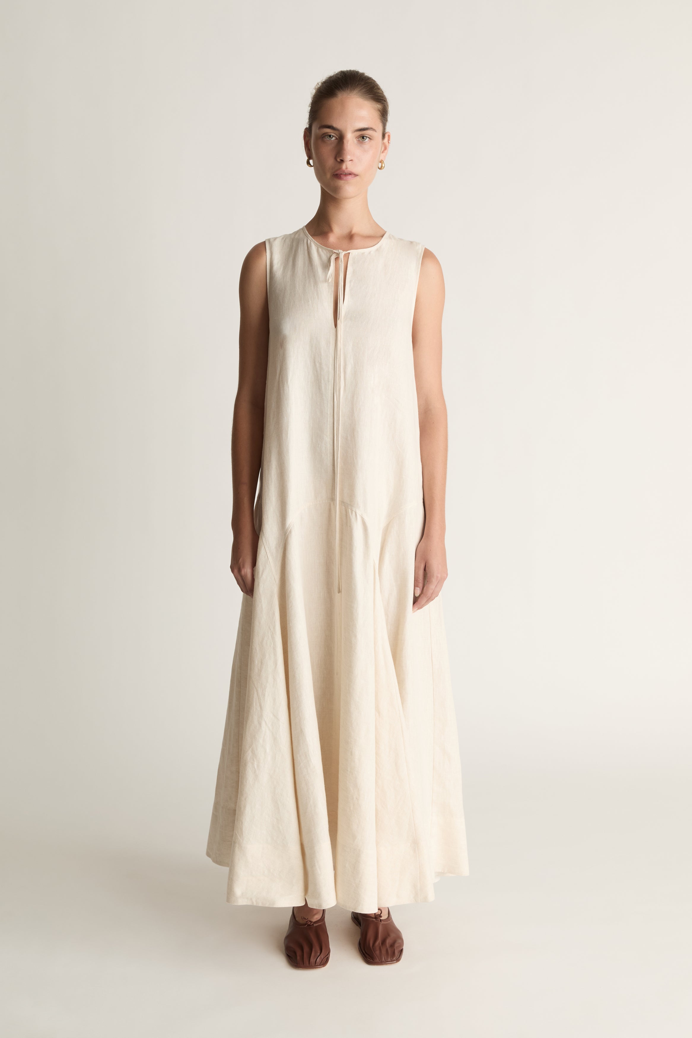 Woman wearing a long beige dress on a white background
