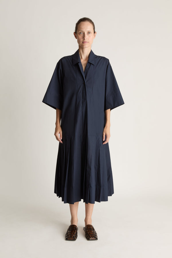 Woman wearing a navy blue dress on a plain background