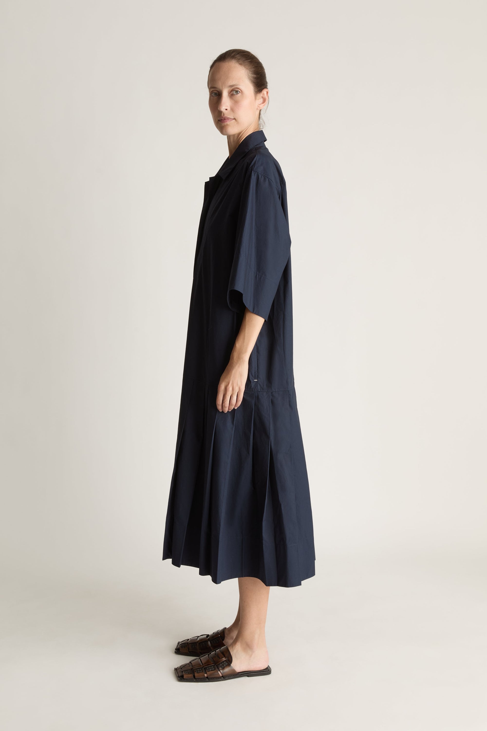 Woman wearing a navy blue dress on a plain background