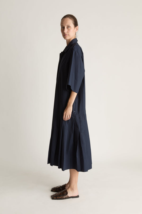 Woman wearing a navy blue dress on a plain background