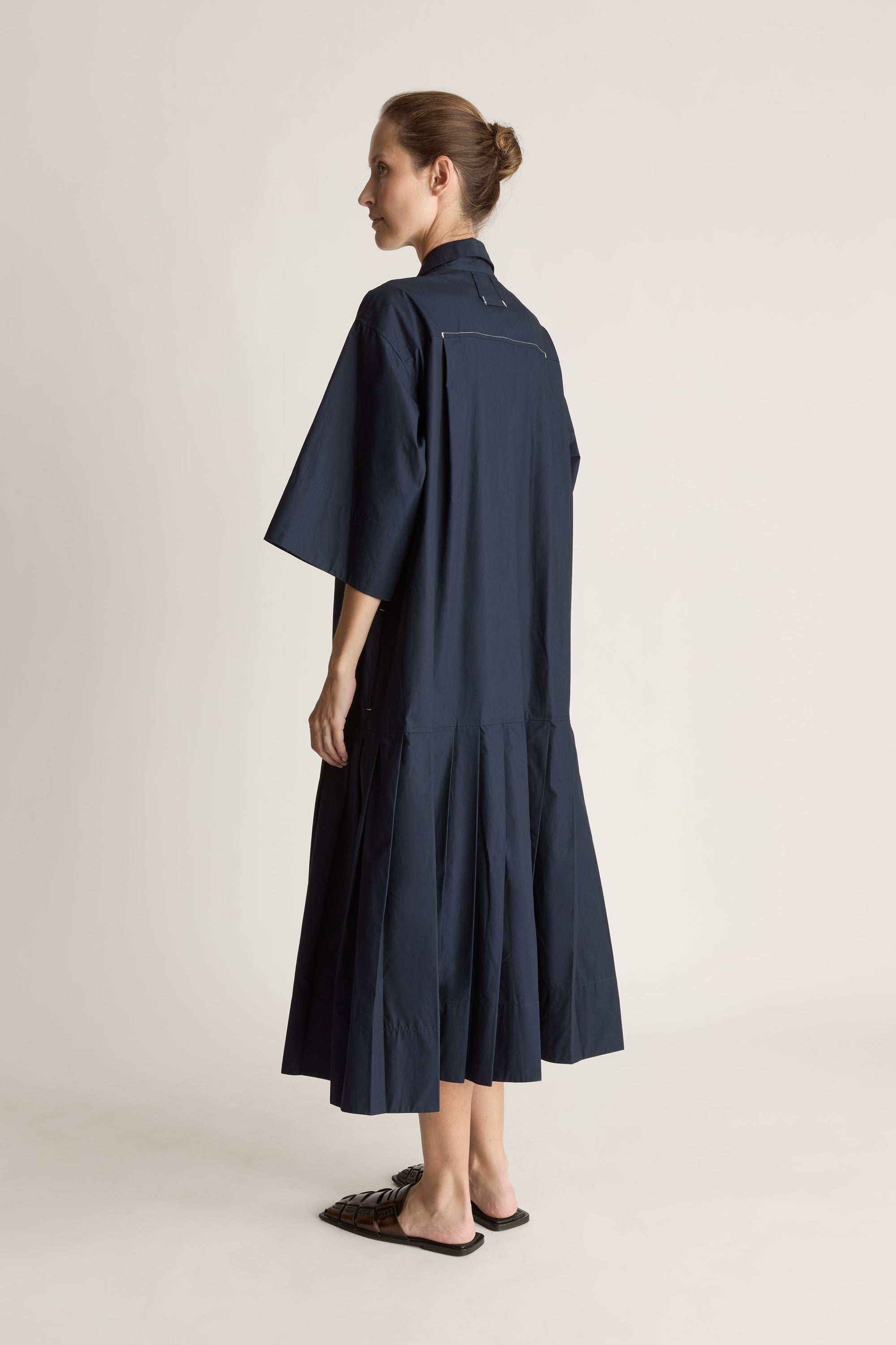 Woman wearing a navy blue dress on a plain background