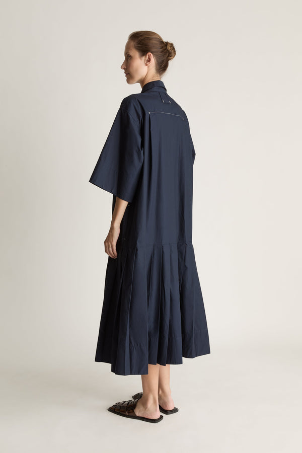 Woman wearing a navy blue dress on a plain background