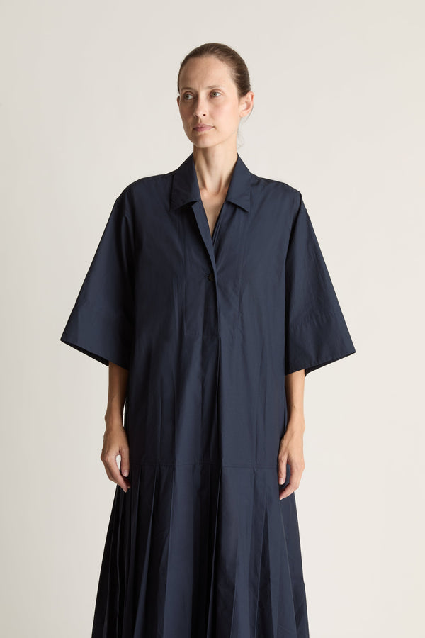 Woman wearing a navy blue dress on a plain background