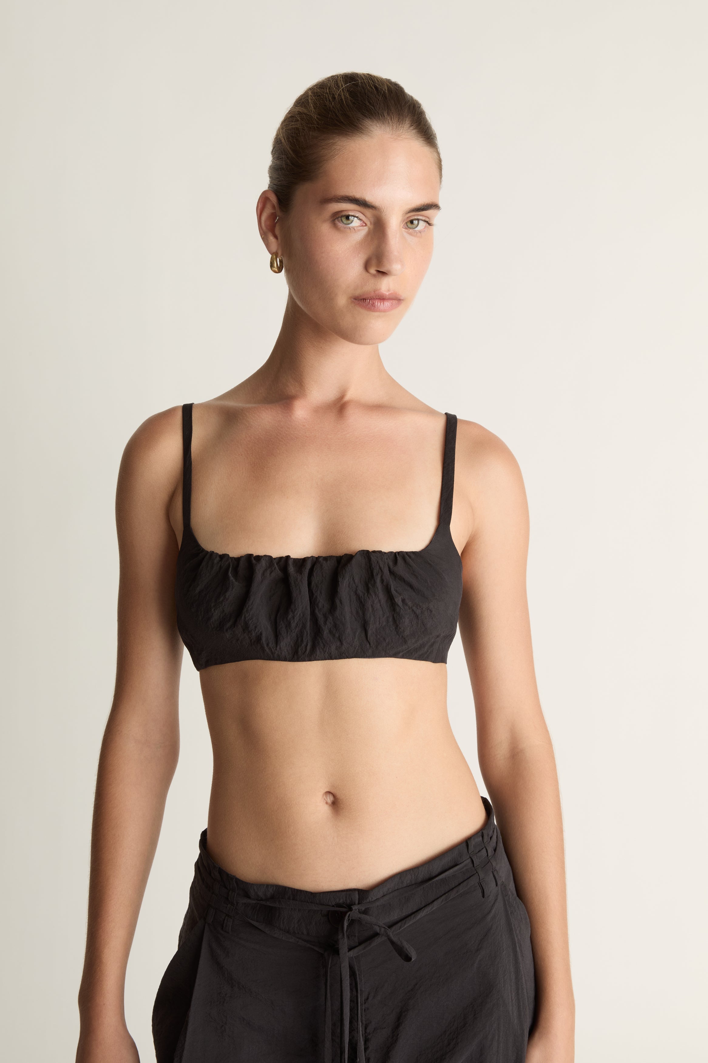 Woman wearing a cropped black top and wide-leg pants on a plain background