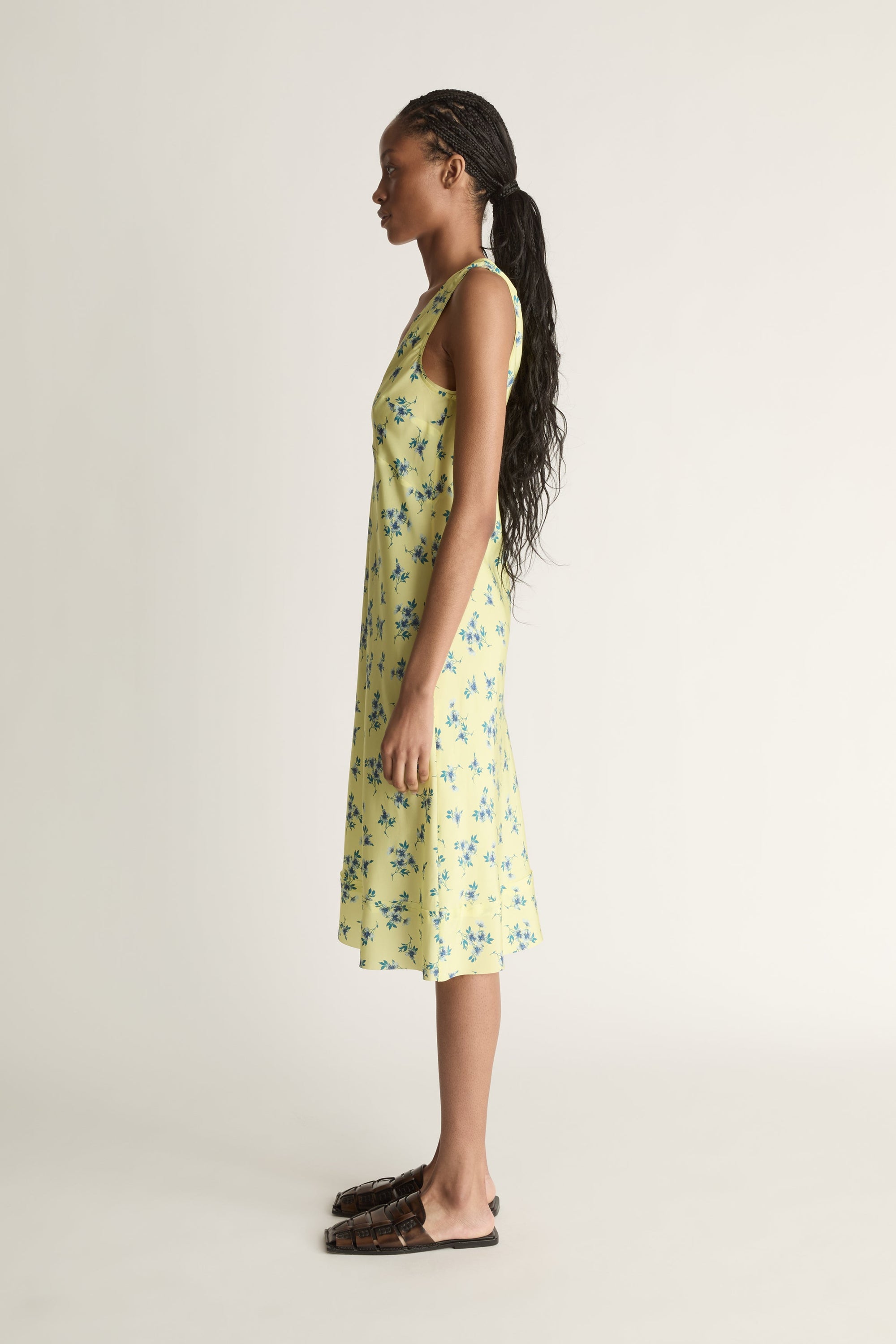 Woman wearing a yellow floral dress on a white background
