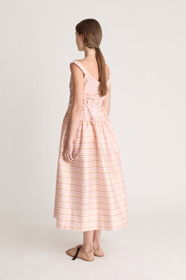 Woman wearing a sleeveless dress with a striped pattern on a plain background