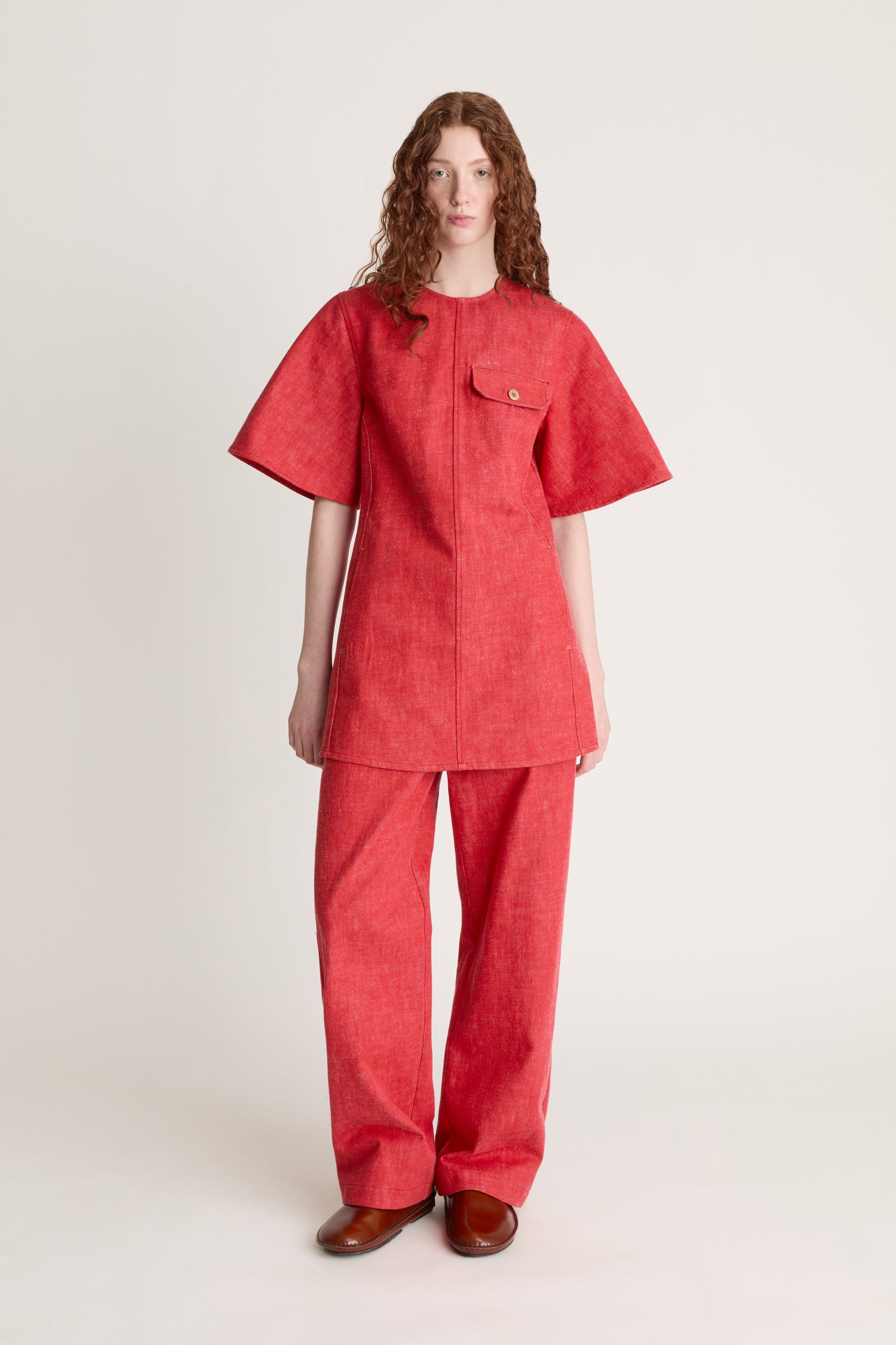 Person wearing a reddress and red pants on a white background