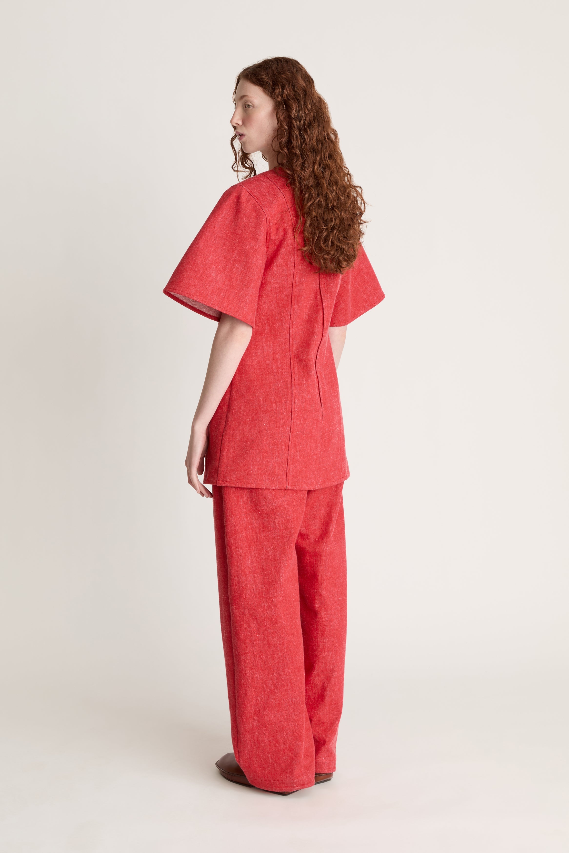 Person wearing a reddress and red pants on a white background