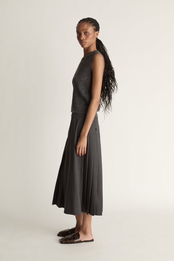 Woman wearing a dark gray sleeveless v neck knit top and skirt on a white background