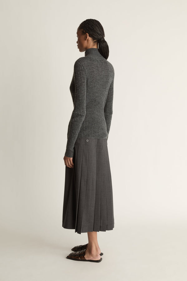 Woman wearing a gray ribbed sweater and skirt on a white background