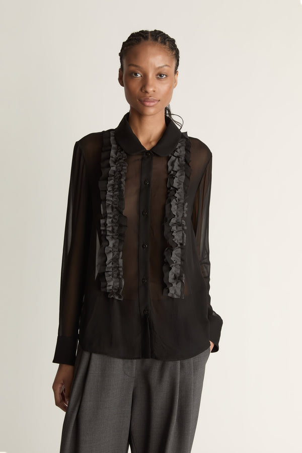Woman wearing Black sheer shirt and grey trousers on a white background