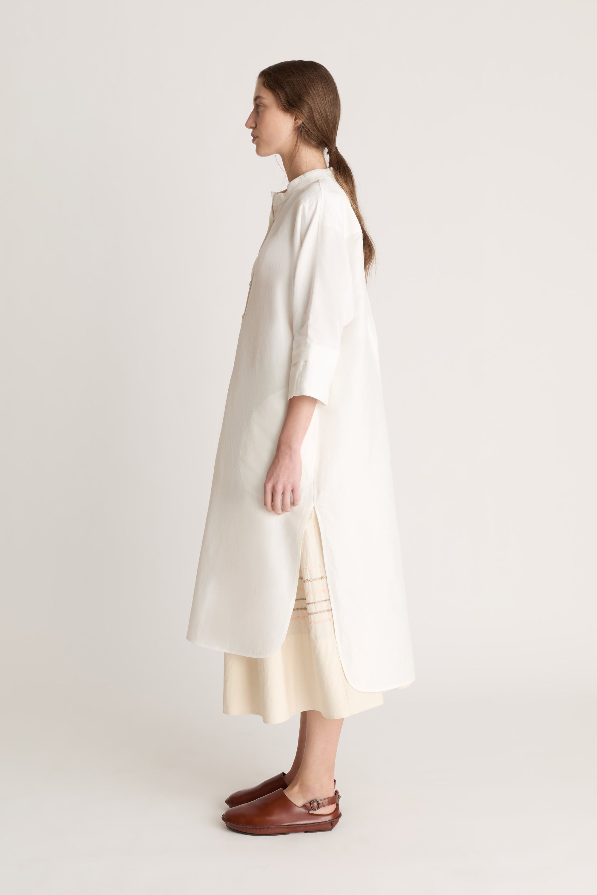 Woman wearing a white tunic with a beige skirt on a white background