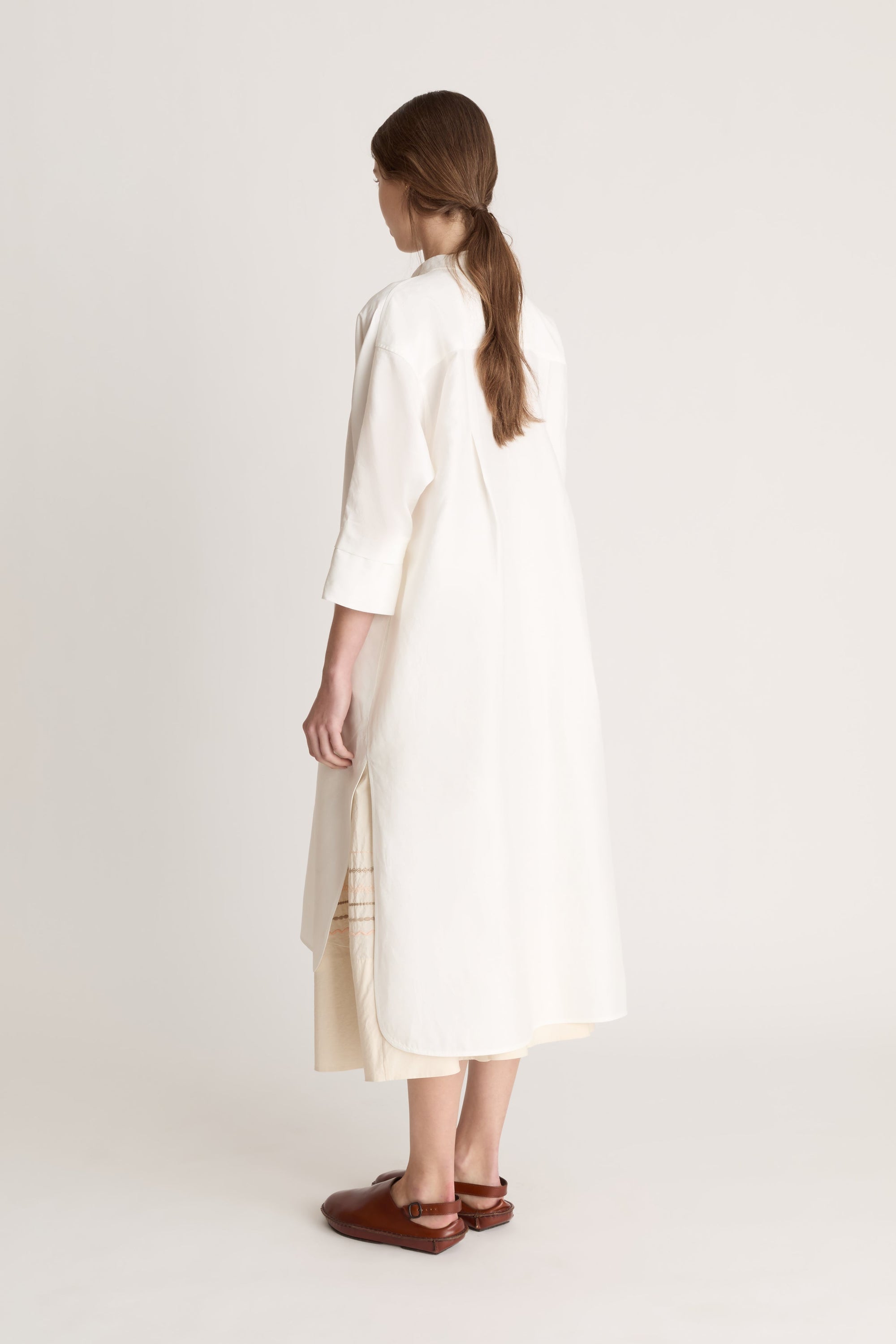 Woman wearing a white tunic with a beige skirt on a white background