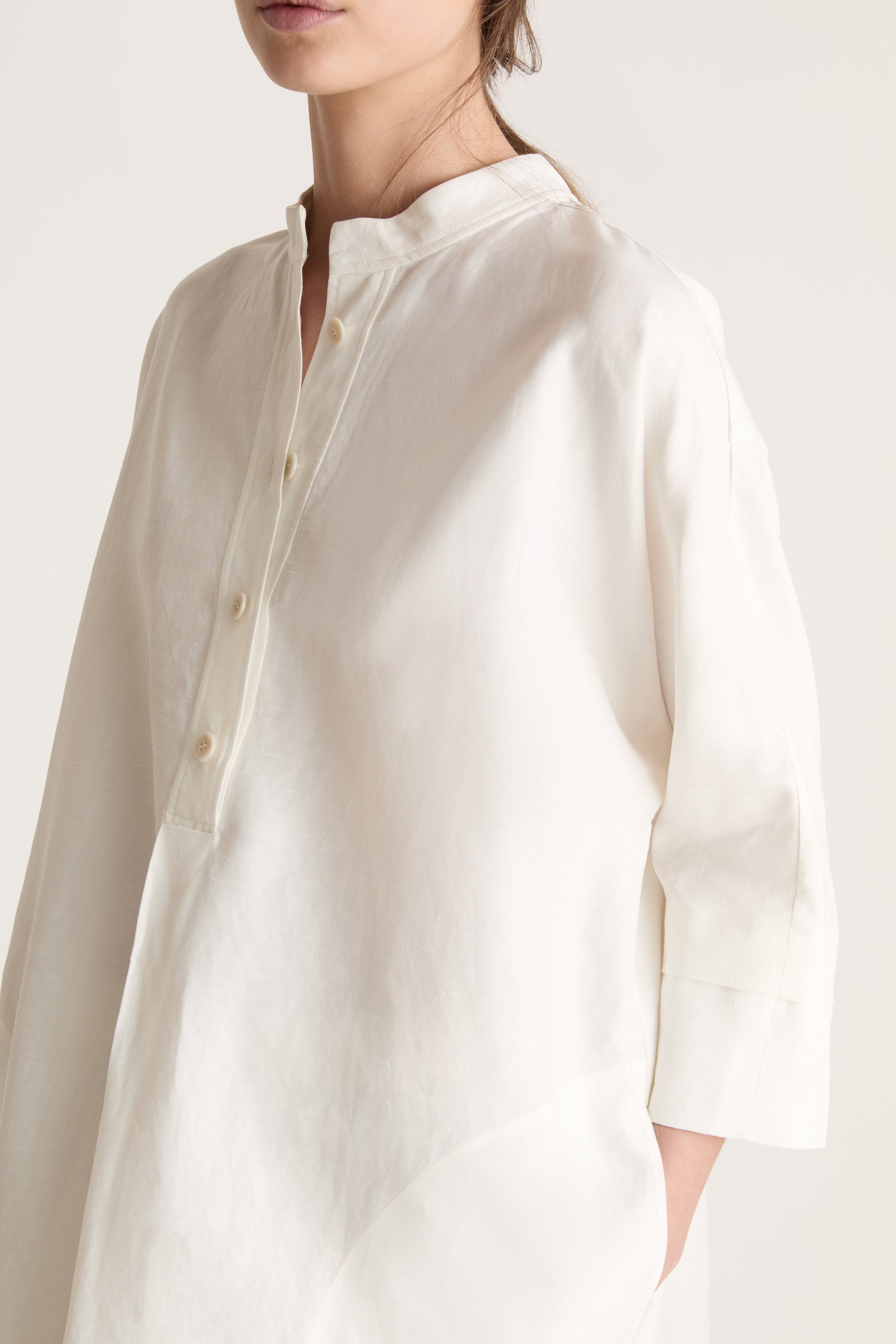 Woman wearing a white tunic with a beige skirt on a white background