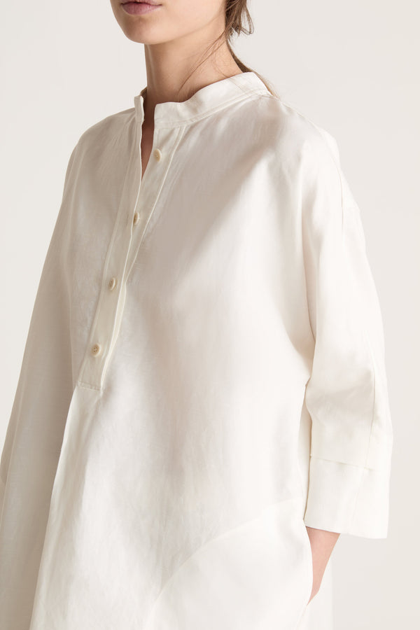 Woman wearing a white tunic with a beige skirt on a white background