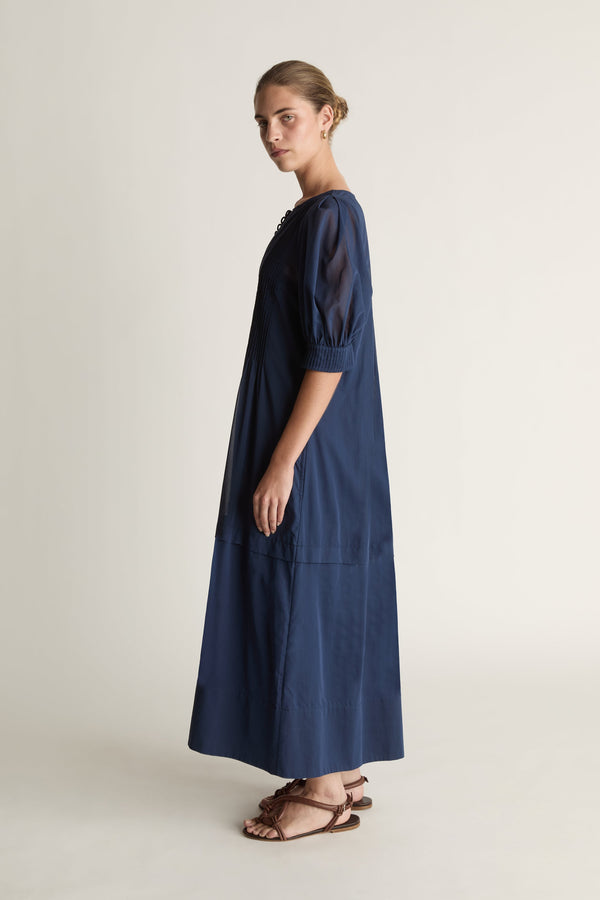 Woman wearing a navy blue dress on a plain background