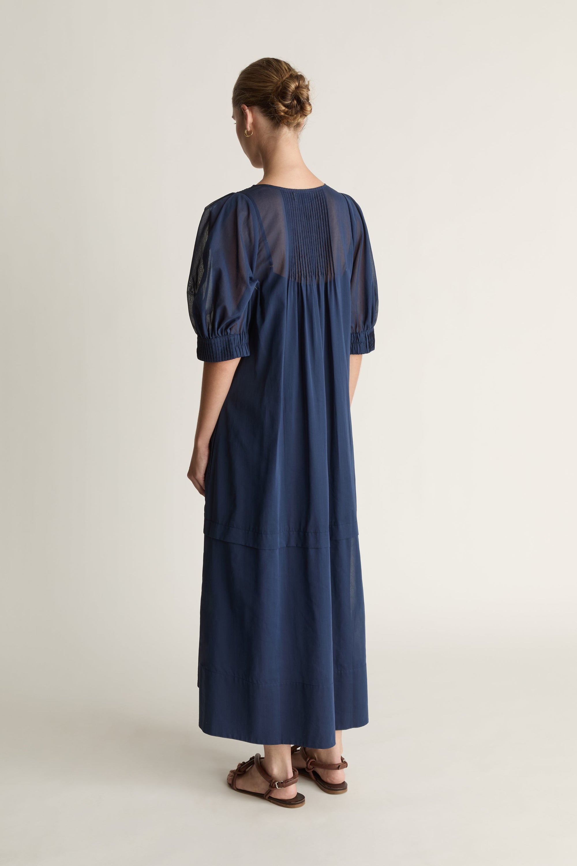 Woman wearing a navy blue dress on a plain background