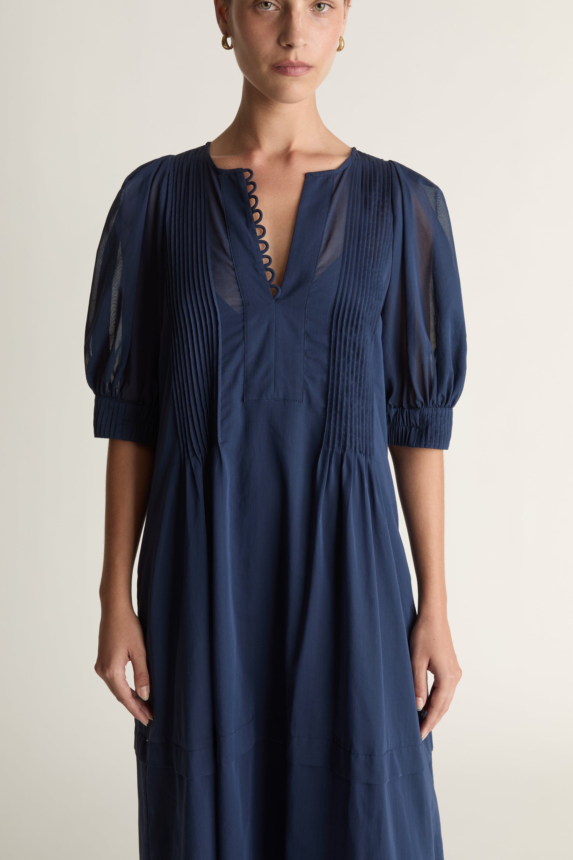 Woman wearing a navy blue dress on a plain background