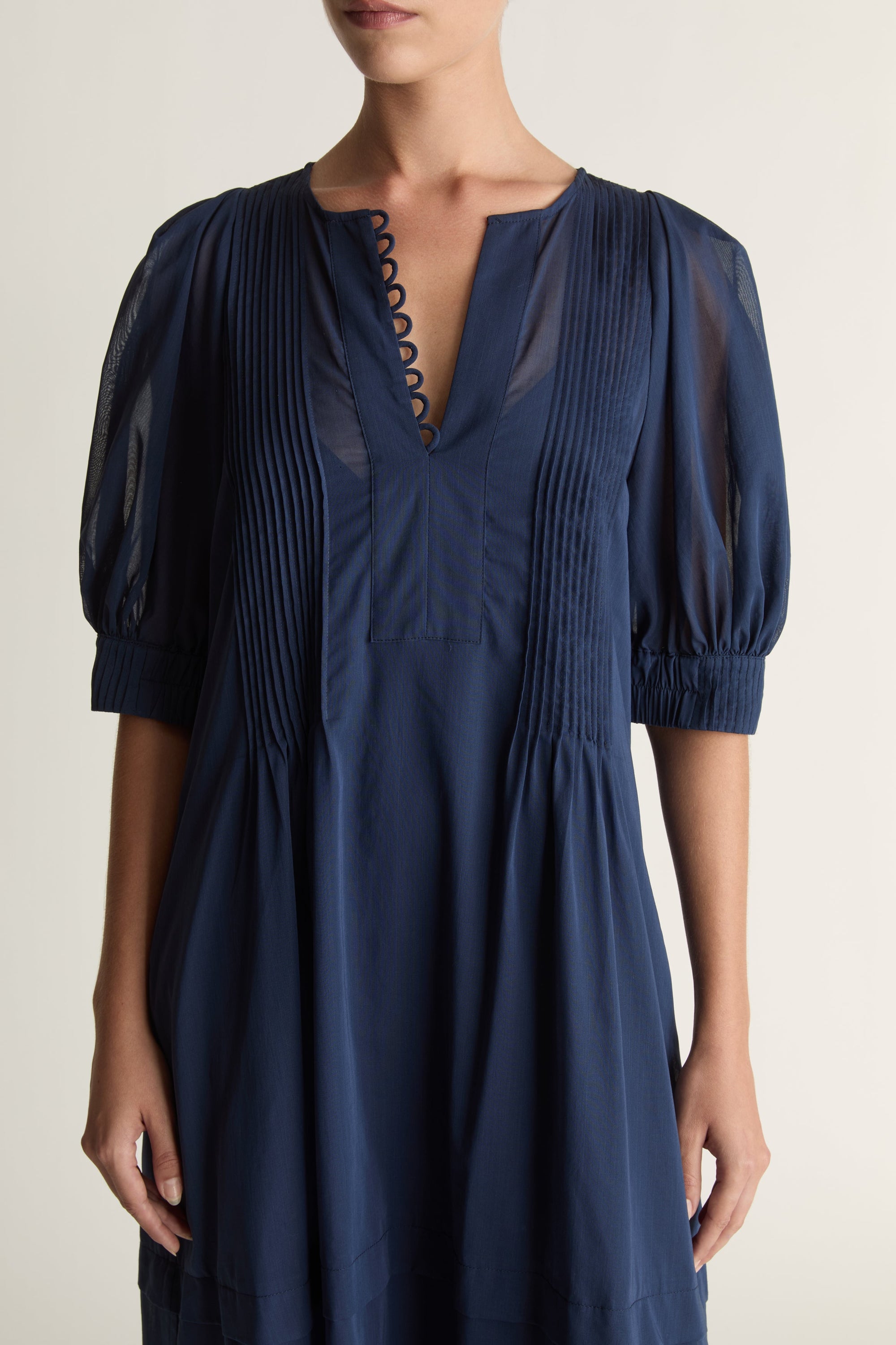 Woman wearing a navy blue dress on a plain background