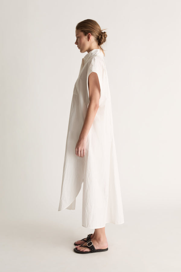 Side view of a white midi shirt dress with wide cap sleeves and a curved, split side hem.