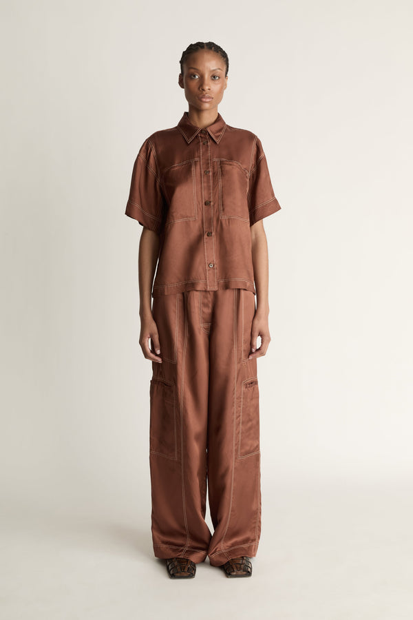 Person wearing a brown shirt and pants on a plain background