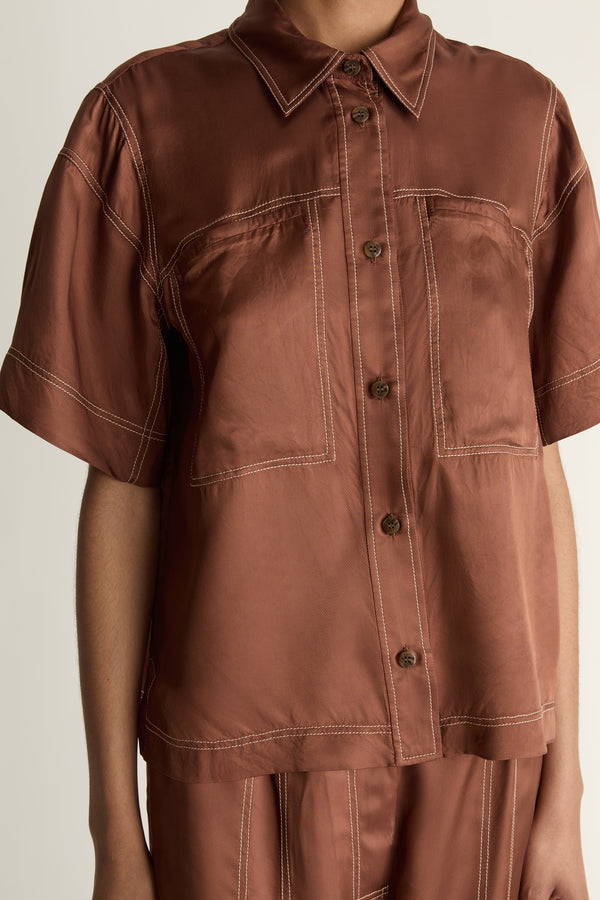 Person wearing a brown shirt and pants on a plain background
