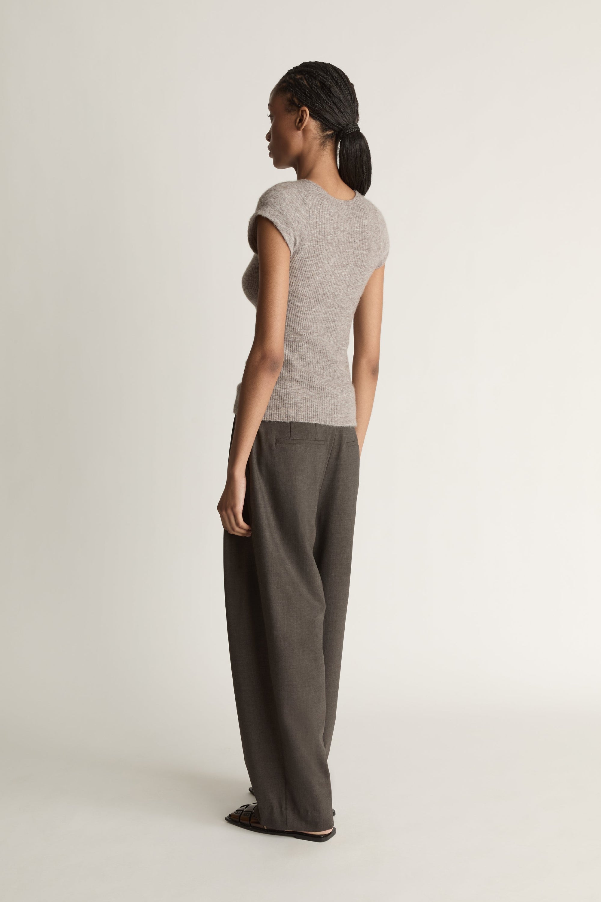 Woman wearing a gray sleeveless top and wide-leg pants on a white background