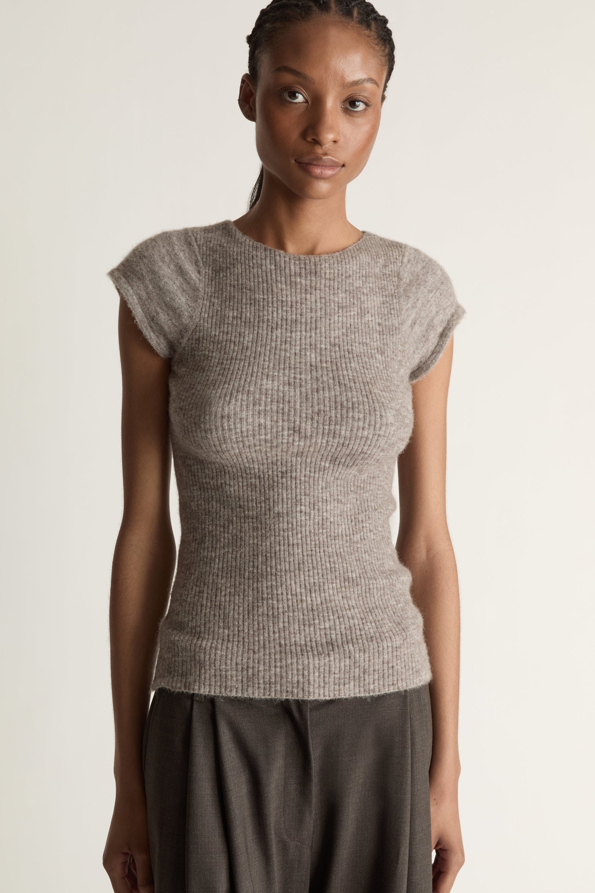 Woman wearing a gray sleeveless top and wide-leg pants on a white background