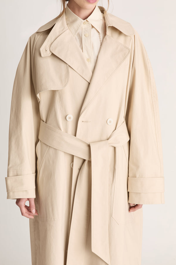 Beige trench coat worn by a person on a white background